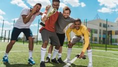 happy multiethnic soccer team with goblet standing on soccer pitch