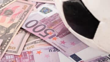 close up view of soccer ball on euro and dollar banknotes, sport